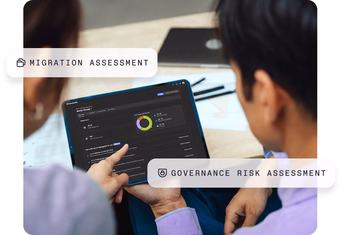 Two people reviewing a tablet screen showing charts and data on migration and governance risk assessments.