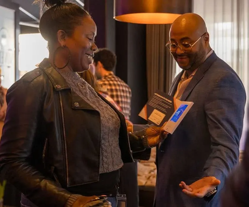 Woman and man smiling looking at a book that the woman is holding