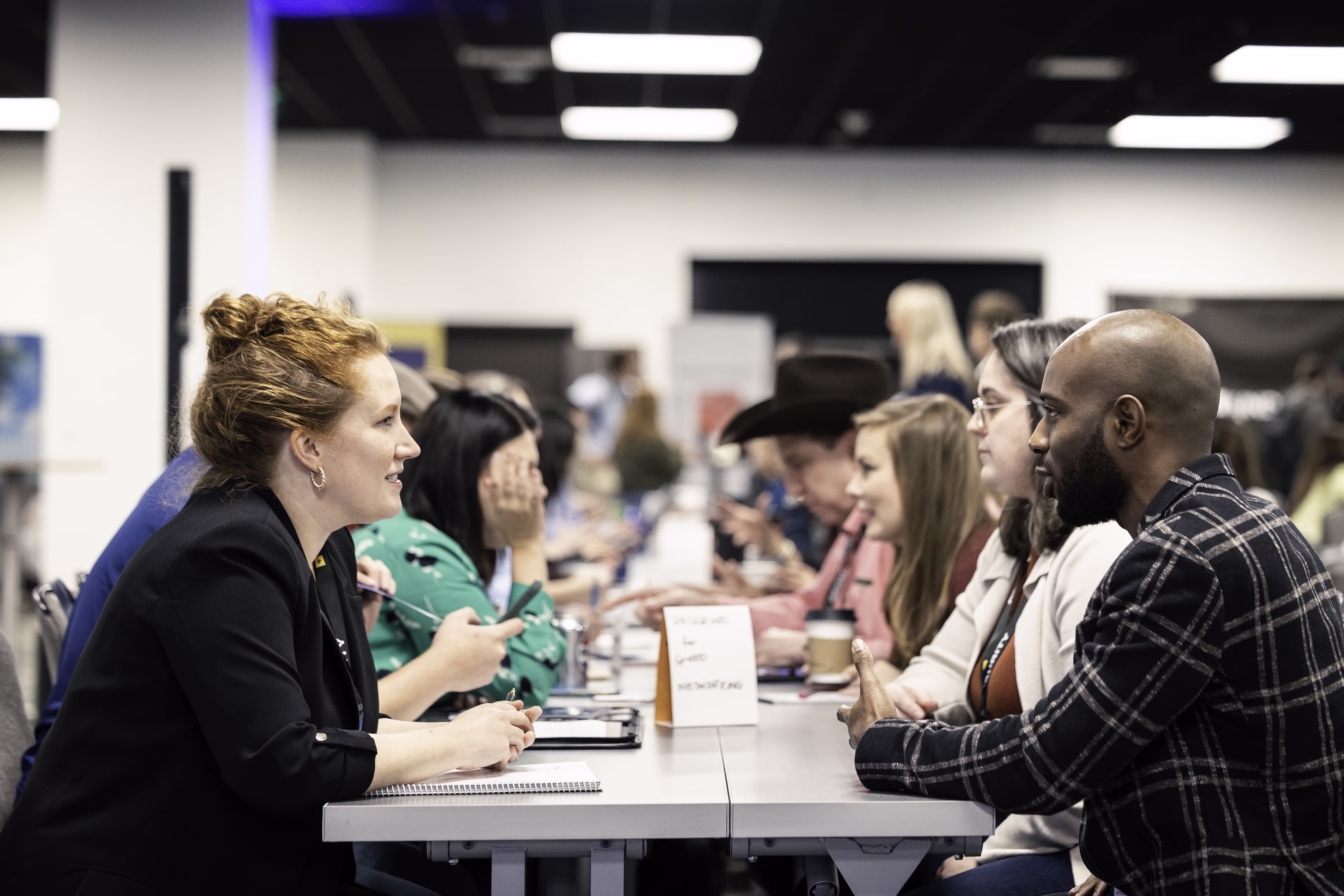 Two rows of people sitting either side of a table talking