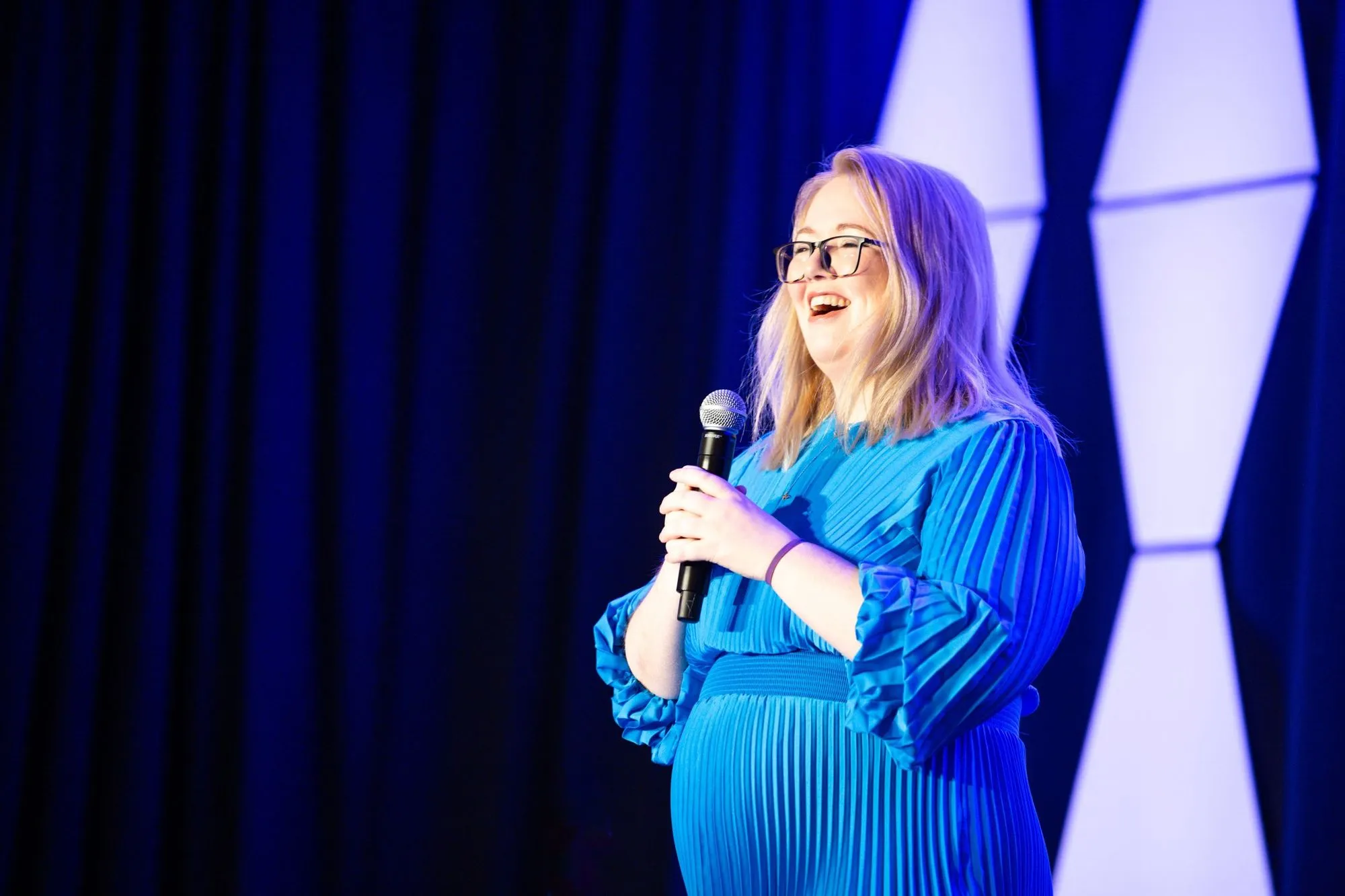 Woman speaking with a microphone on a stage