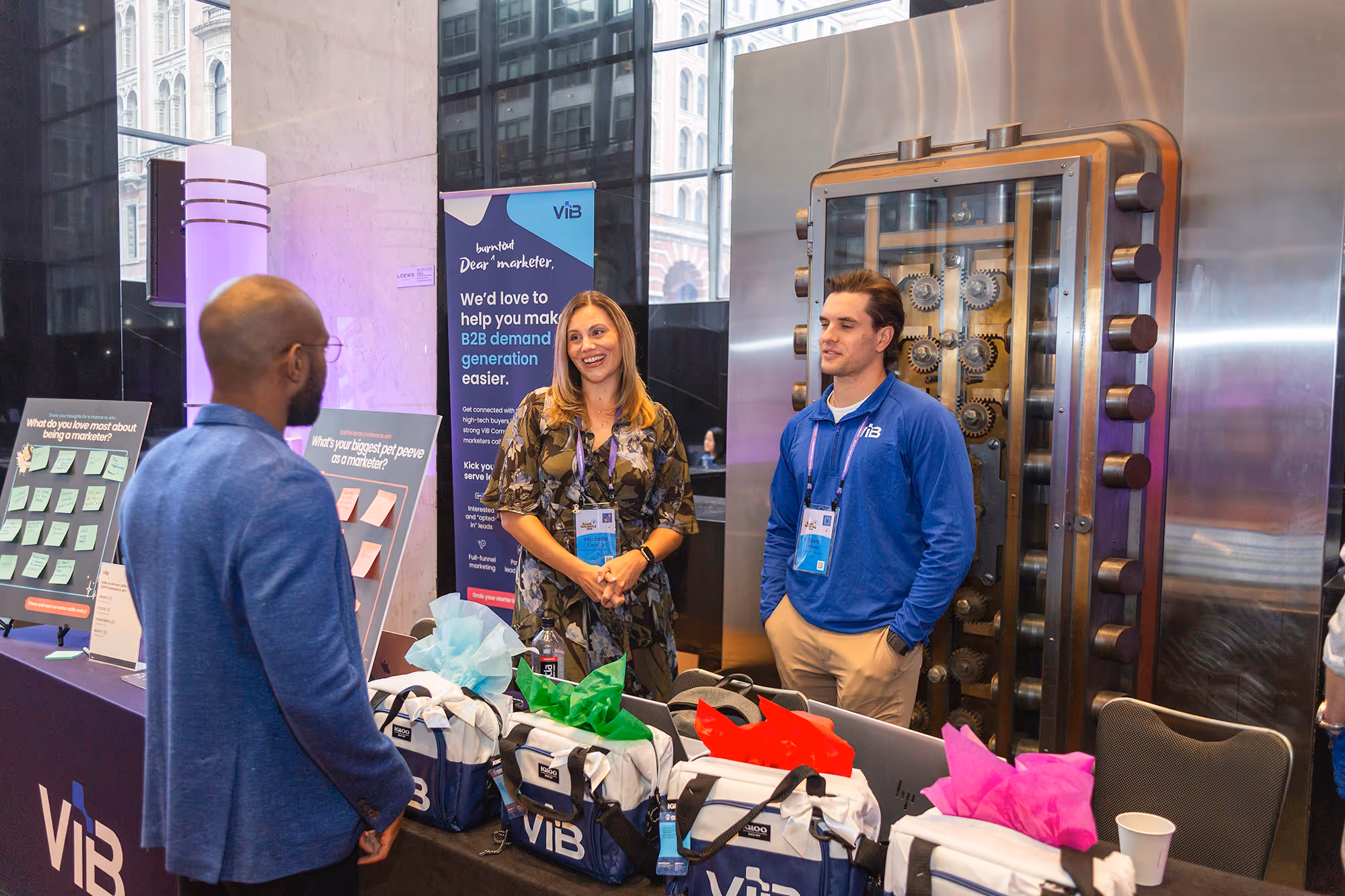 A woman and man on one side of a table with Merch speaking to another man on the other side