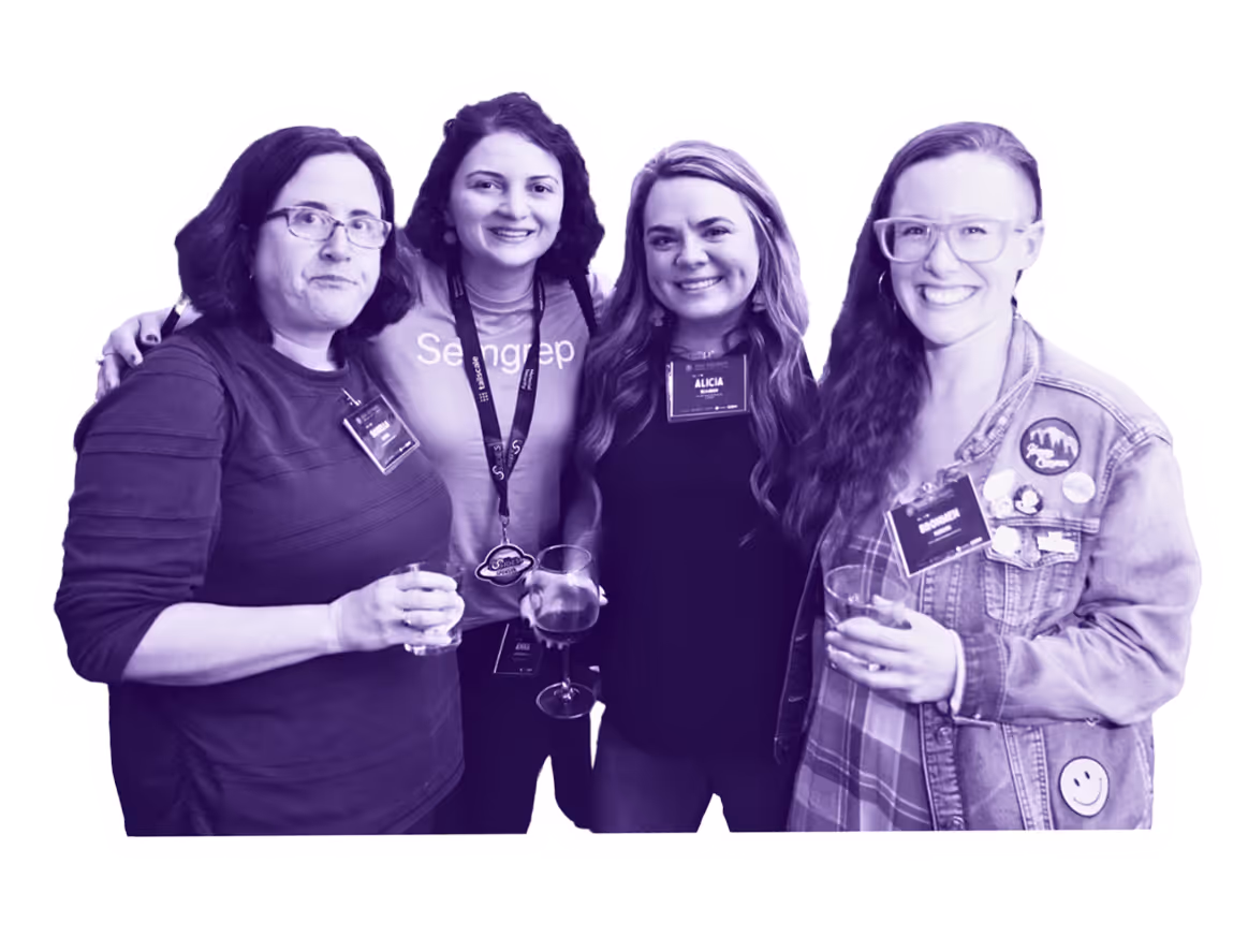 Four women standing close together smiling
