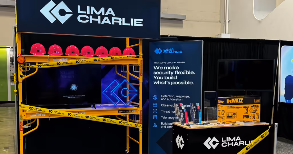 LimaCharlie's booth with table and red hard hats and LimaCharlies merchandise