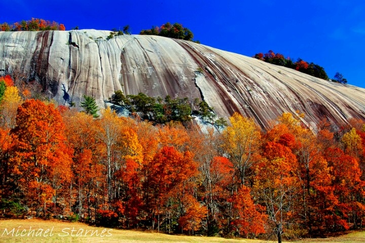 View of Stone Mountain’s granite dome with hikers on the trail and a waterfall in the background