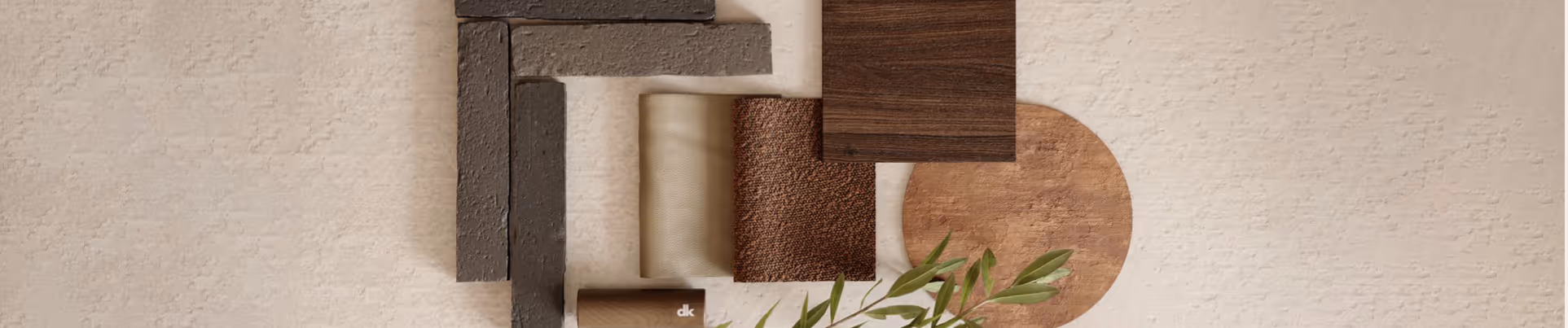 Stalen en materialen in neutrale en aardetinten, waaronder hout, textiel en stenen, gerangschikt op een beige oppervlak met een groene tak.
