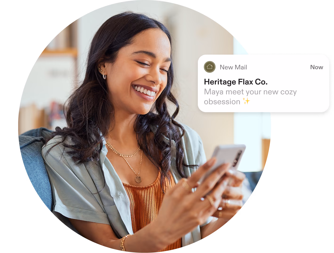 Smiling woman holding a smartphone with a notification from Heritage Flax Co. about a cozy obsession.