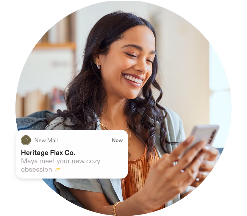 Smiling woman holding a smartphone with a notification from Heritage Flax Co. about a cozy obsession.