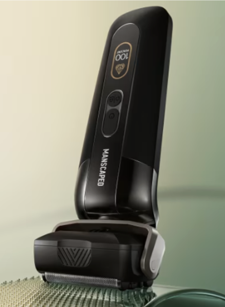 Black Manscaped electric razor with trimming head on a green textured surface.