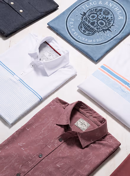 Five neatly folded casual shirts in various colors and patterns laid out on a light surface.