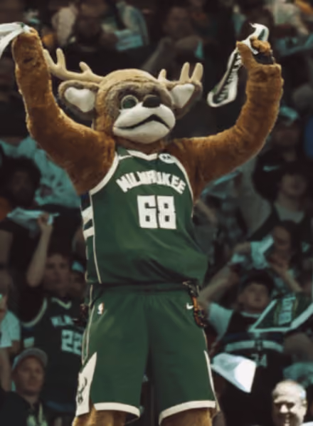 Milwaukee Bucks mascot wearing jersey number 68 cheering with arms raised at a game.