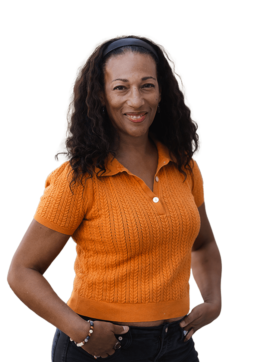 Woman in orange knit top smiling with curly hair and black headband