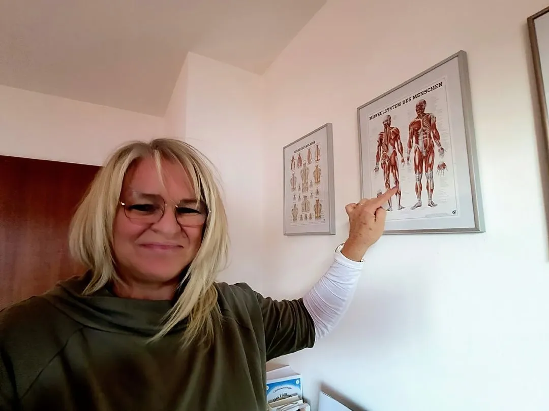 Sabine Jechow erklärt anatomische Details am Muskelplakat – ihr medizinisches Wissen unterstreicht ihre Qualifikation im Heilpraktiker Coaching und ihre fundierte Begleitung bei körperbezogenen Coaching-Themen.