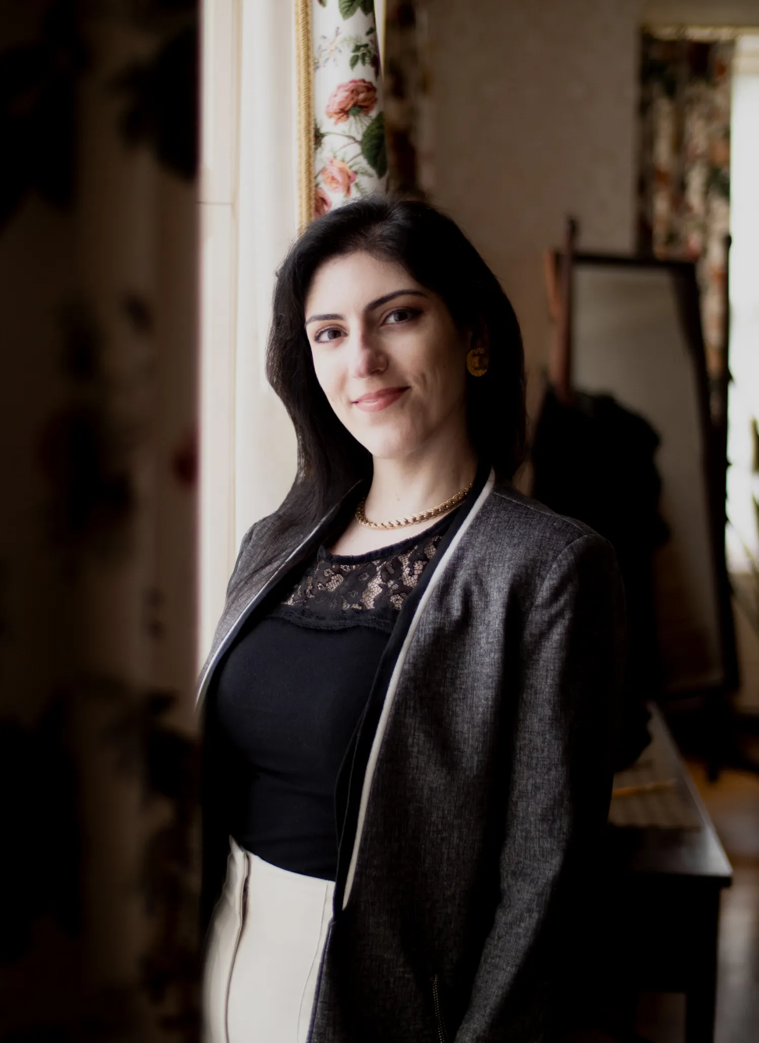 Dr. Irina Gulerez in a gray jacket stands indoors, smiling at the camera.