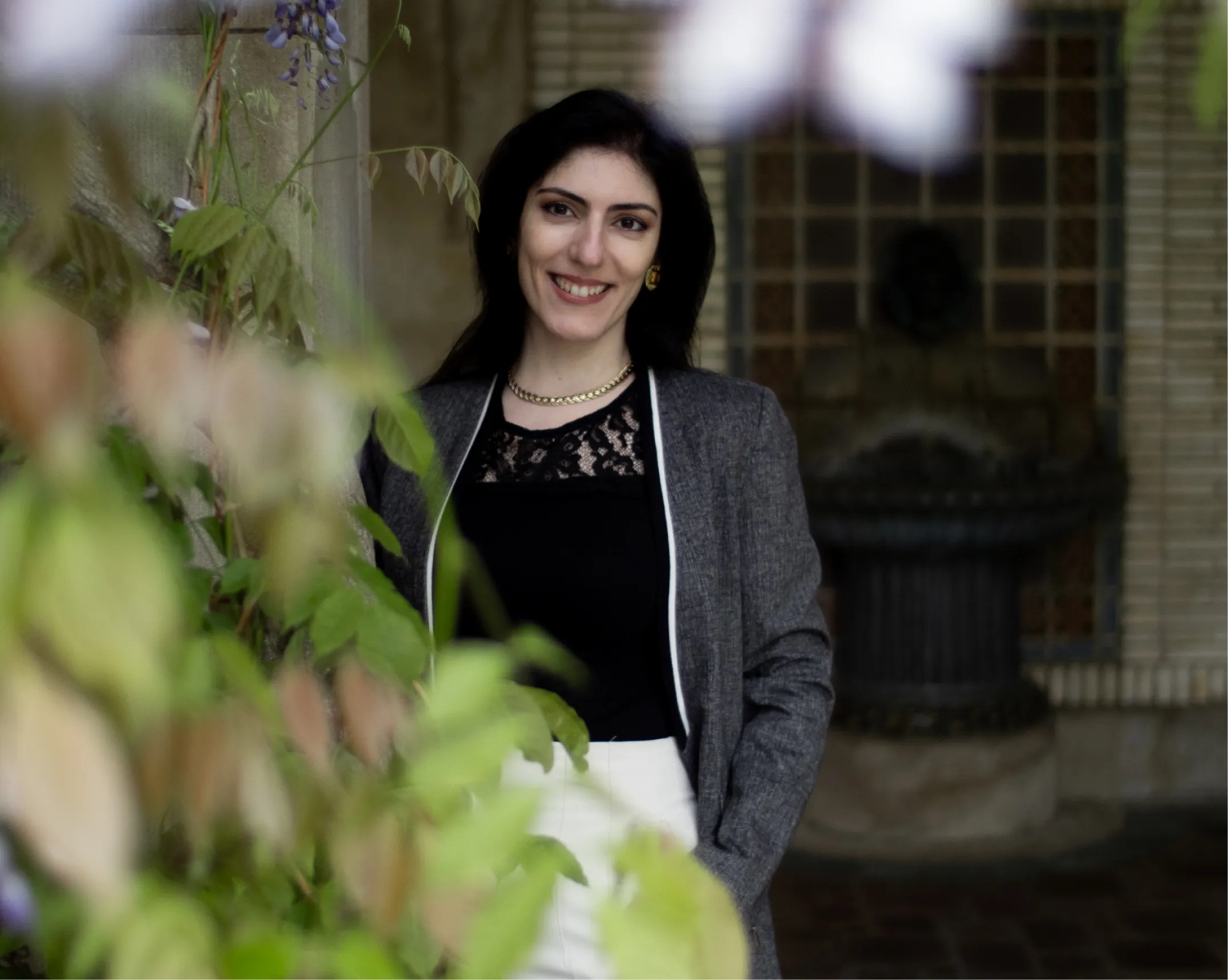 Dr. Irina Gulerez stands in front of foliage, wearing a grey blazer and black top.