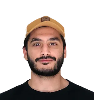 Portrait of a man with a beard wearing a light brown cap and a black shirt, smiling slightly against a transparent background.