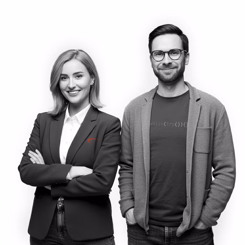 Smiling professional woman with arms crossed and young man wearing glasses and casual blazer standing side by side.