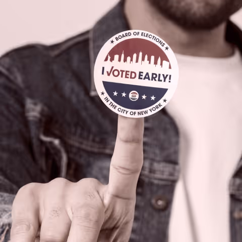 A man holding up a sticker that reads "I voted early"