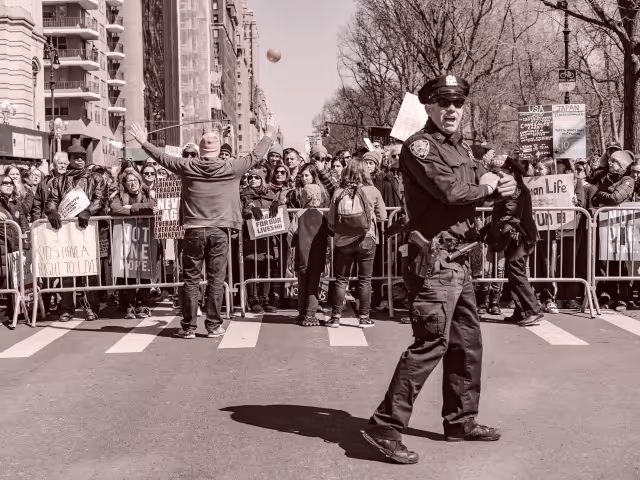 NYPD police officer in front of a crowd of protestors on a street