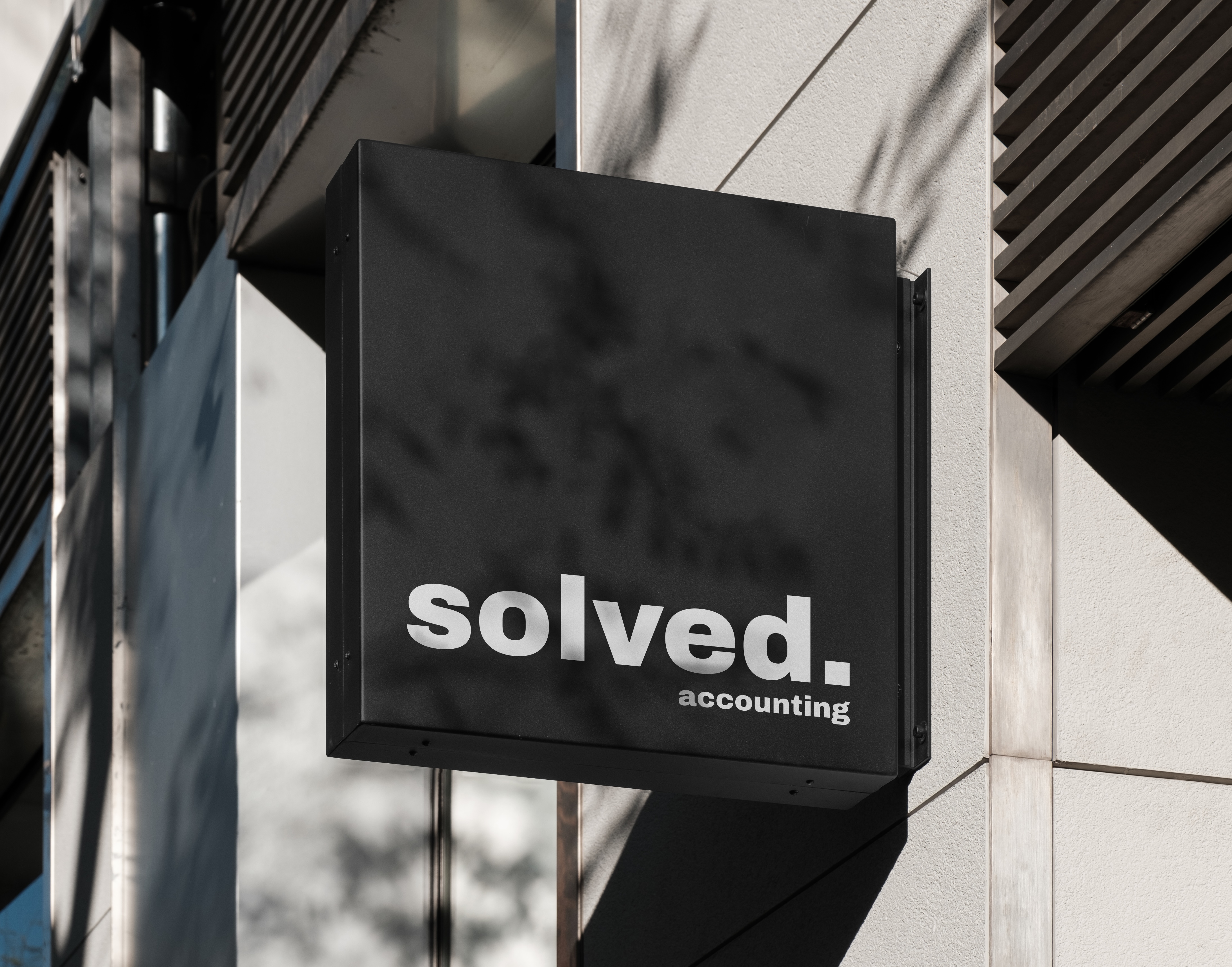 Black building sign displaying the Solved Accounting logo mounted on an exterior wall.
