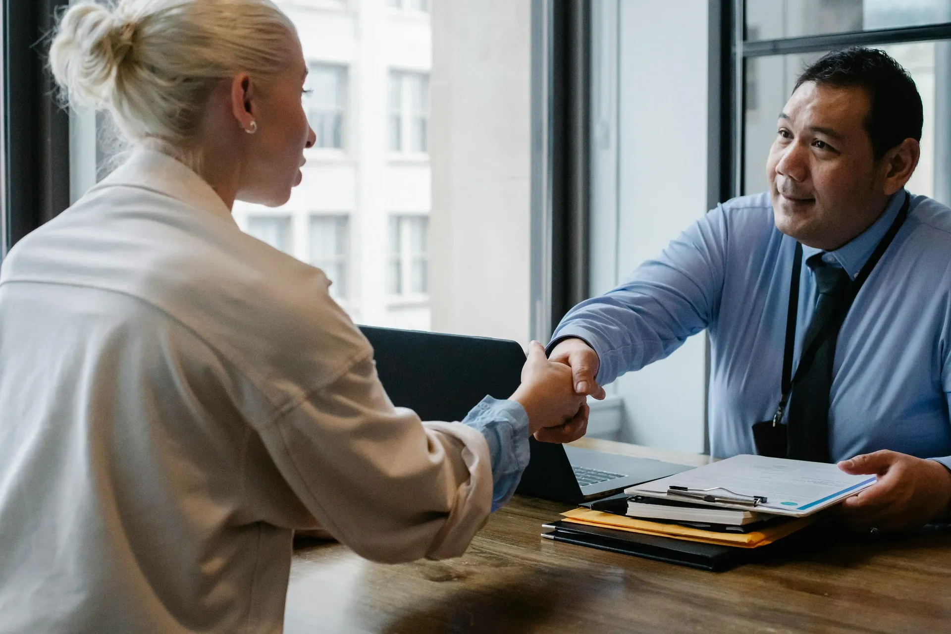Business professionals shaking hands after a successful recruitment interview, partnership agreement, or hiring decision.