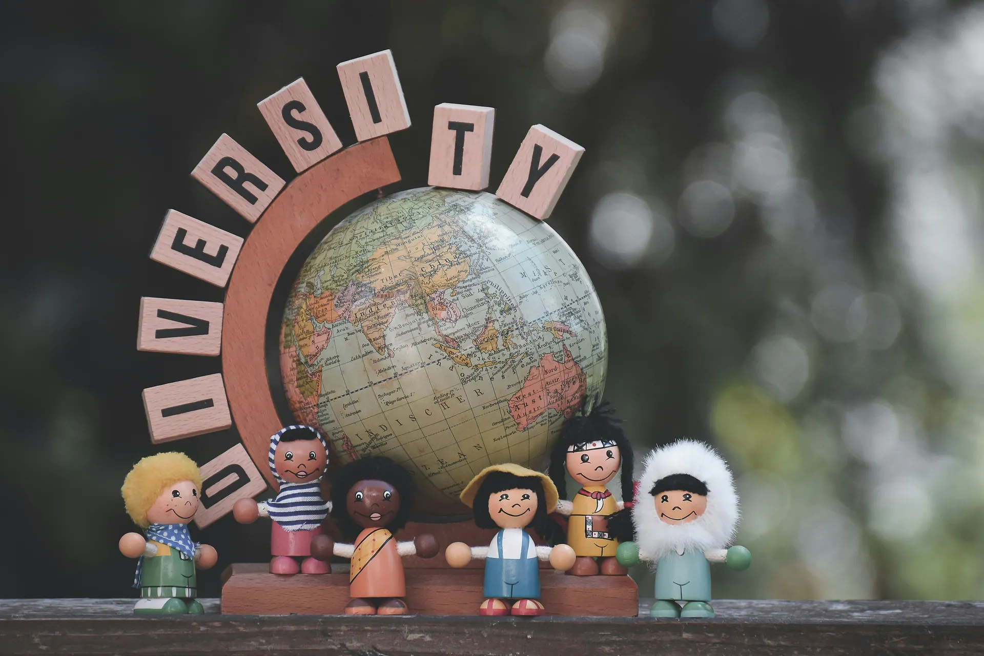 Miniature globe surrounded by diverse toy figures symbolizing inclusion and global unity