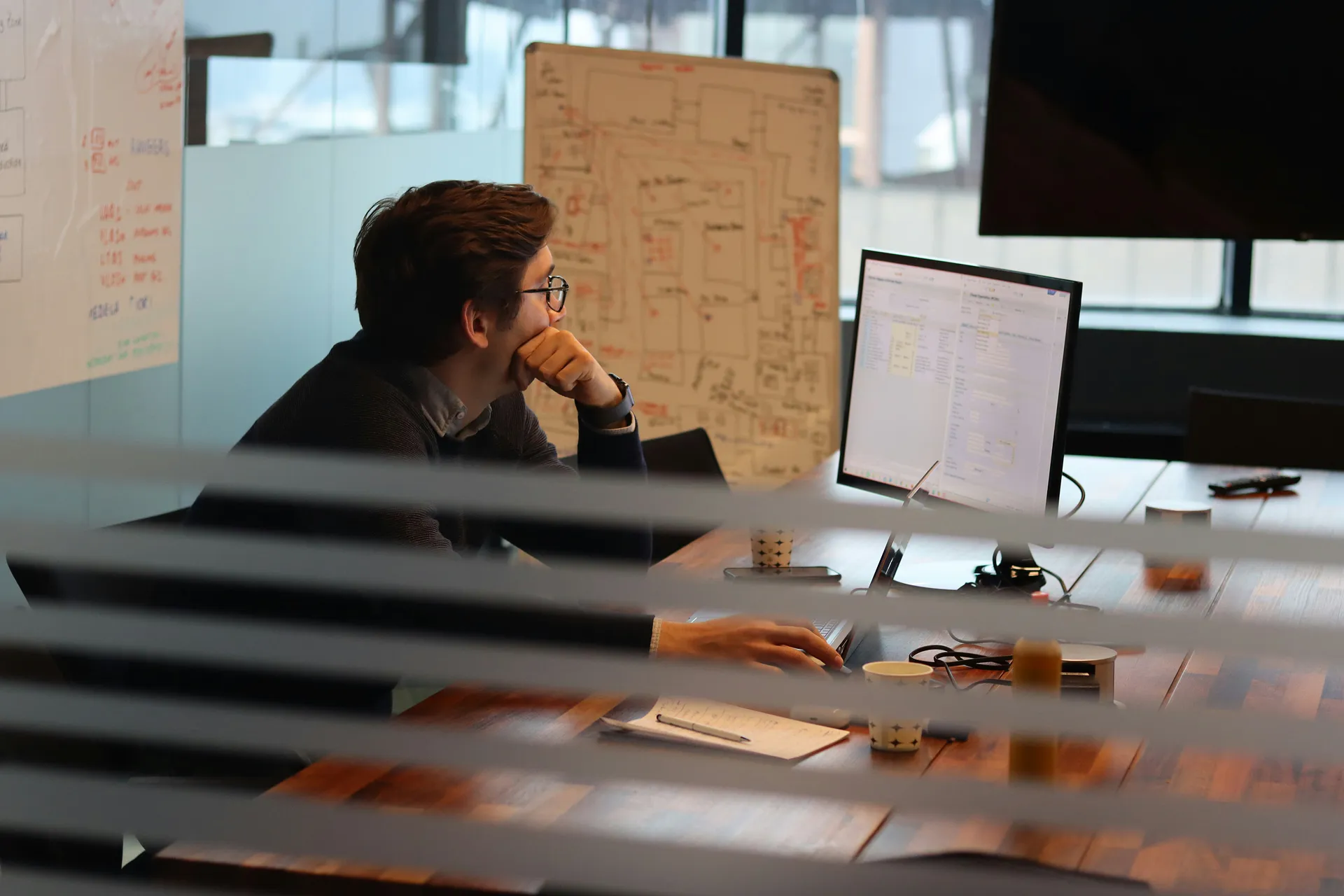 Focused professional working on a computer in a modern office with planning notes on a whiteboard