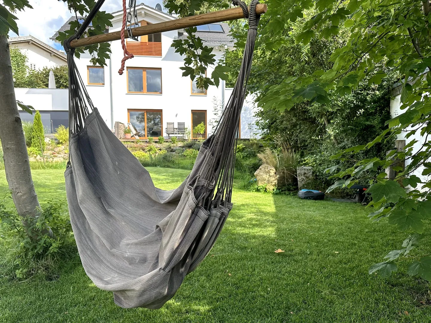 Hängesessel im Garten, dahinter das Haus der Ferienwohnung
