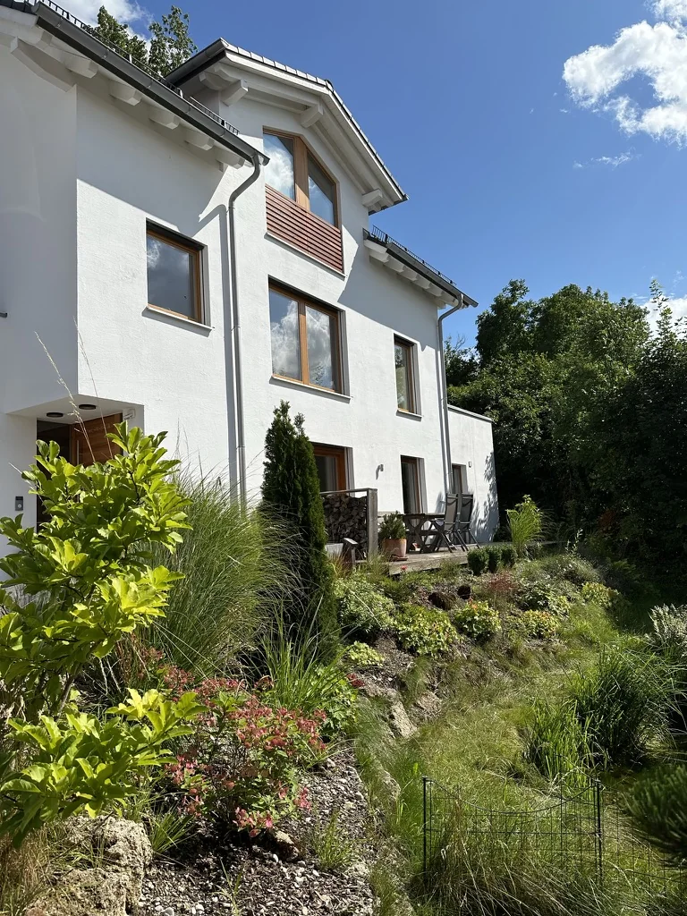 Haus der Ferienwohnung mit Terrasse und bepflanztem Hang im Sommer