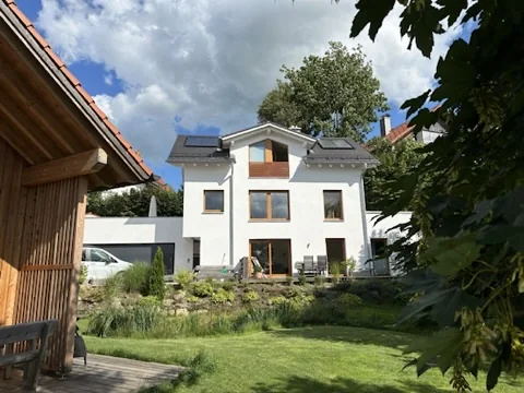 Blick vom Holzchalet über den Garten auf das Haus der Ferienwohnung