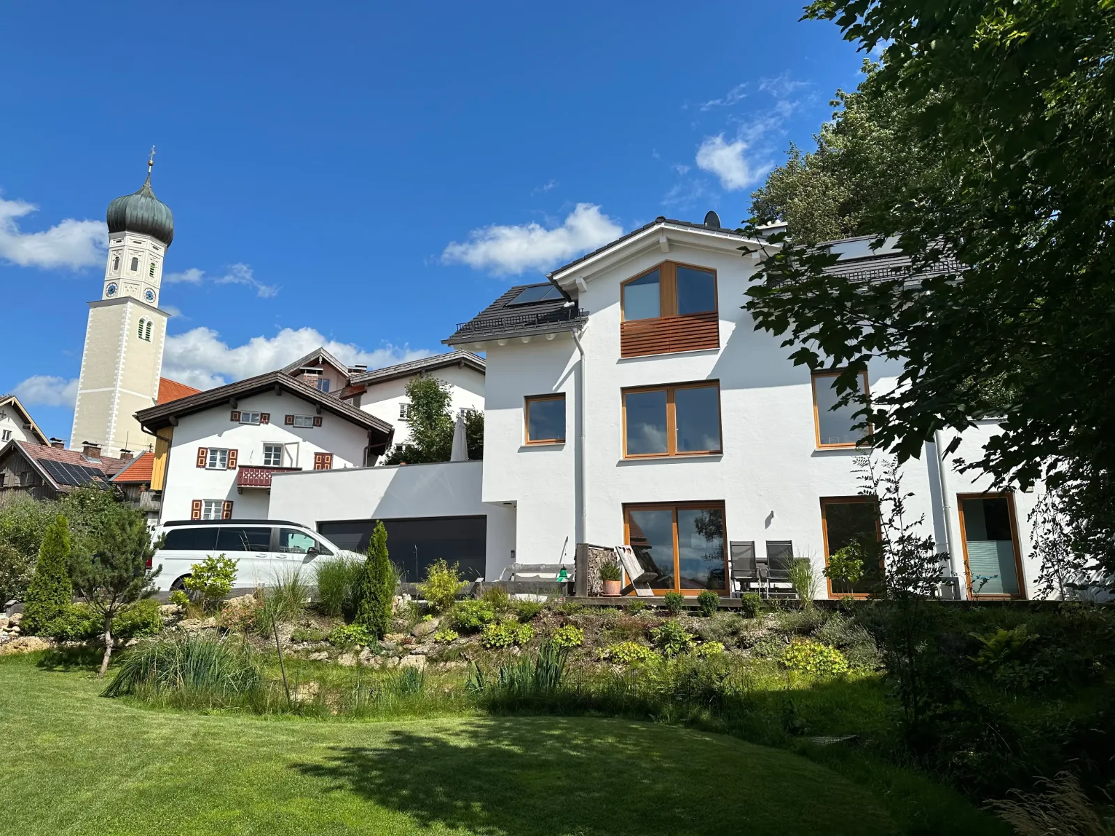 Haus der Ferienwohnung mit Garten, daneben der Kirchturm von Königsdorf