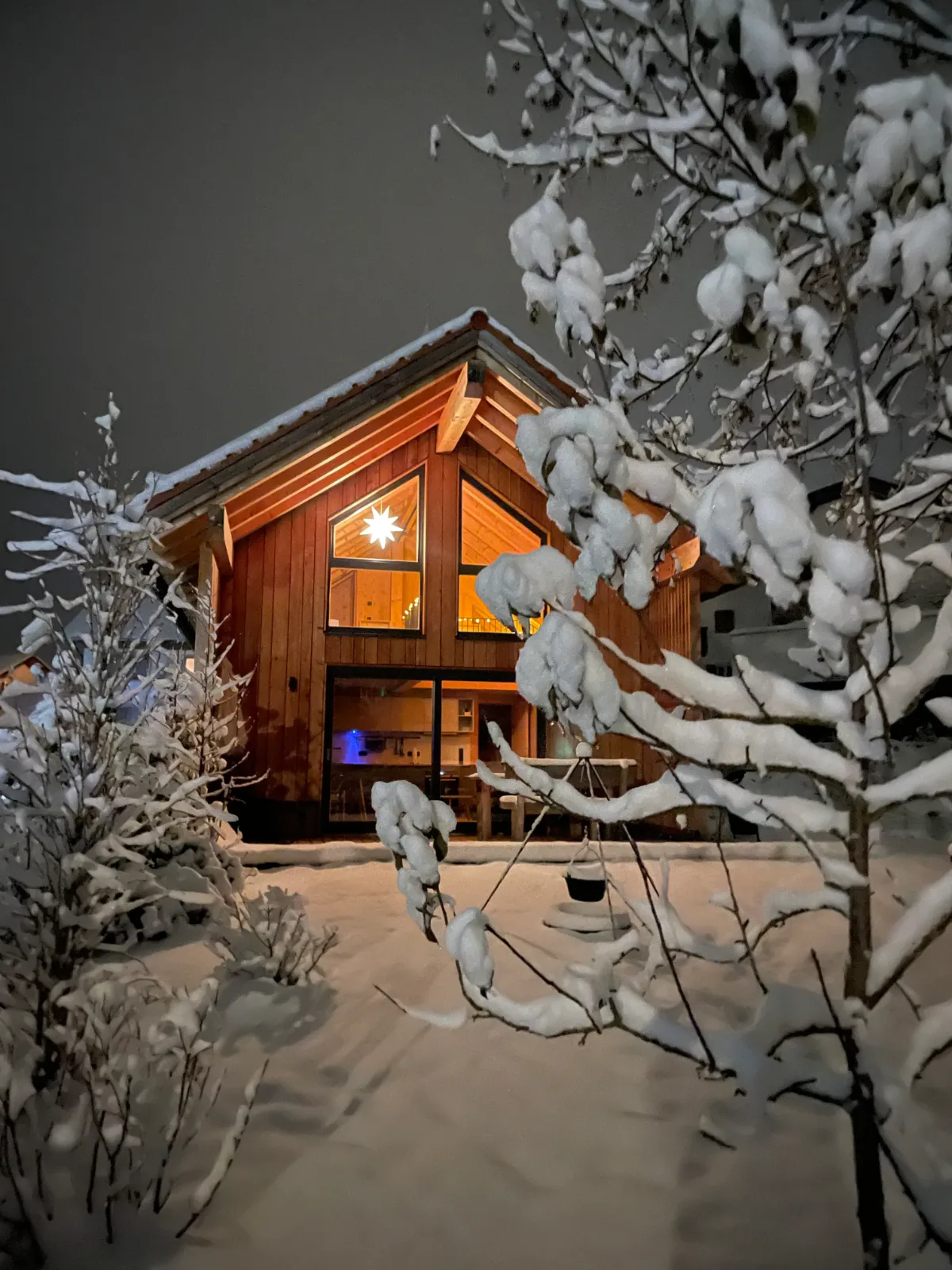 Chalet in einer verschneiten Winternacht mit leuchtendem Stern im Giebelfenster