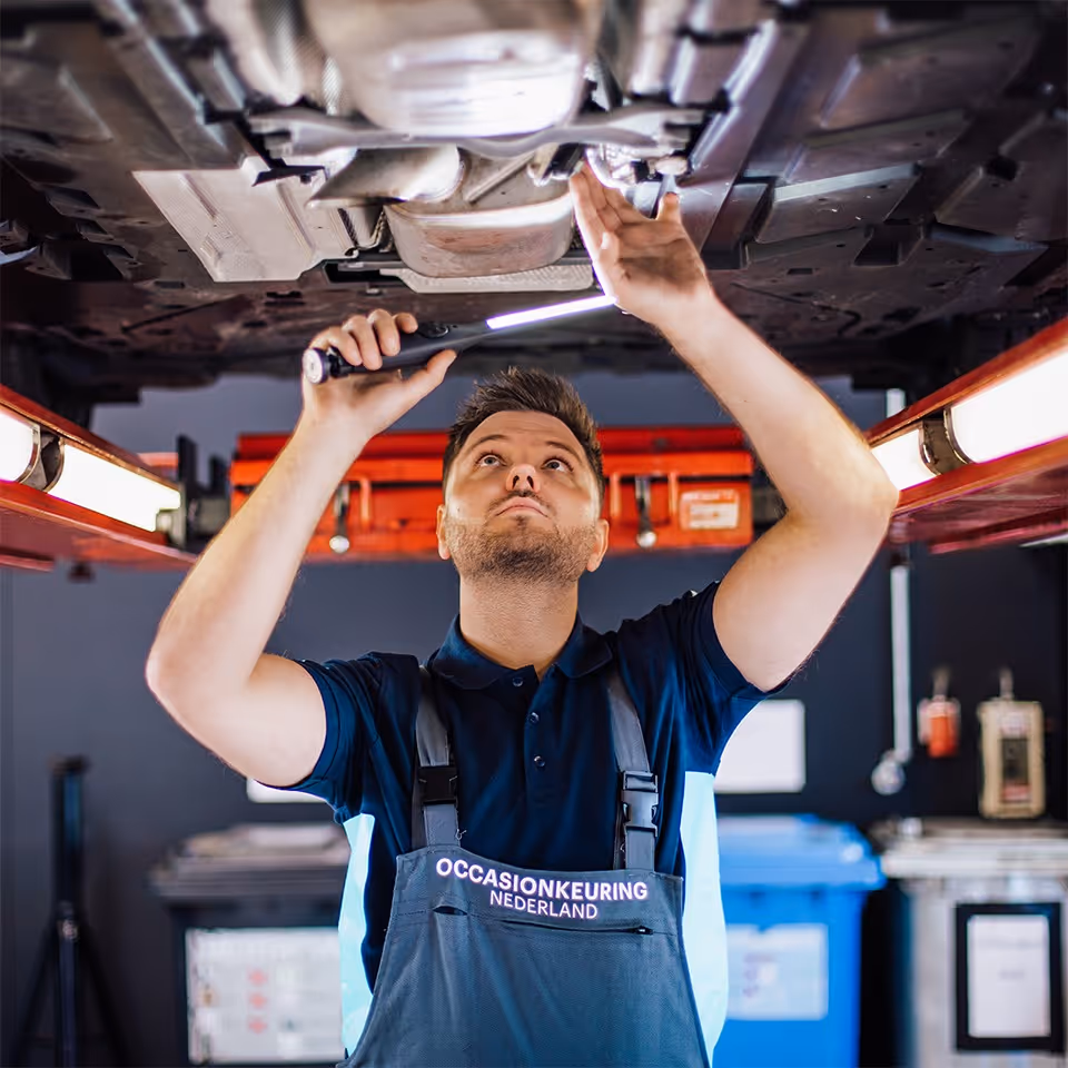 Keurmeester controleert de onderzijde van een camper tijdens een aankoopkeuring