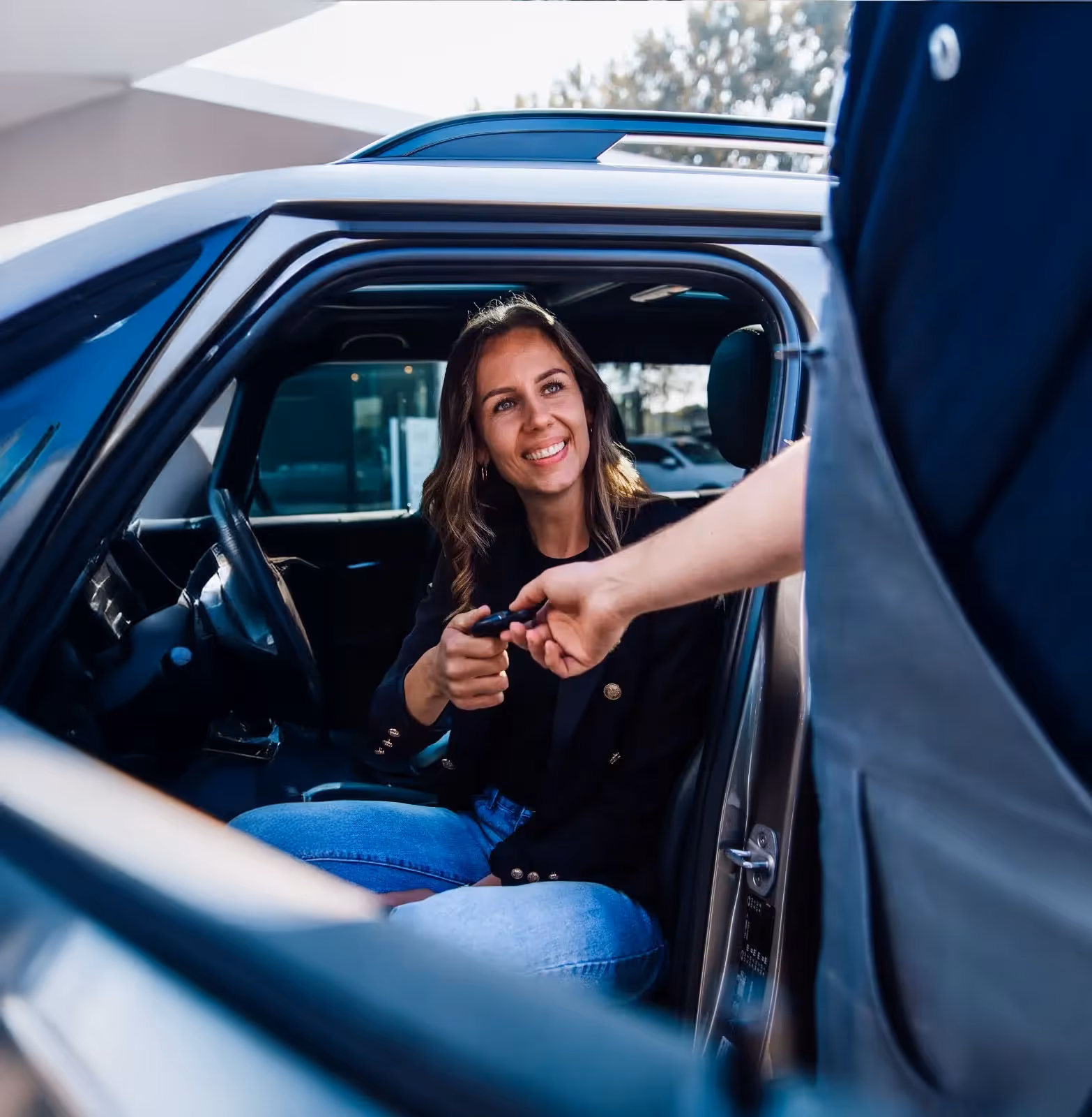 Vrouw in auto geeft de autosleutels aan een keurmeester van Occasionkeuring Nederland