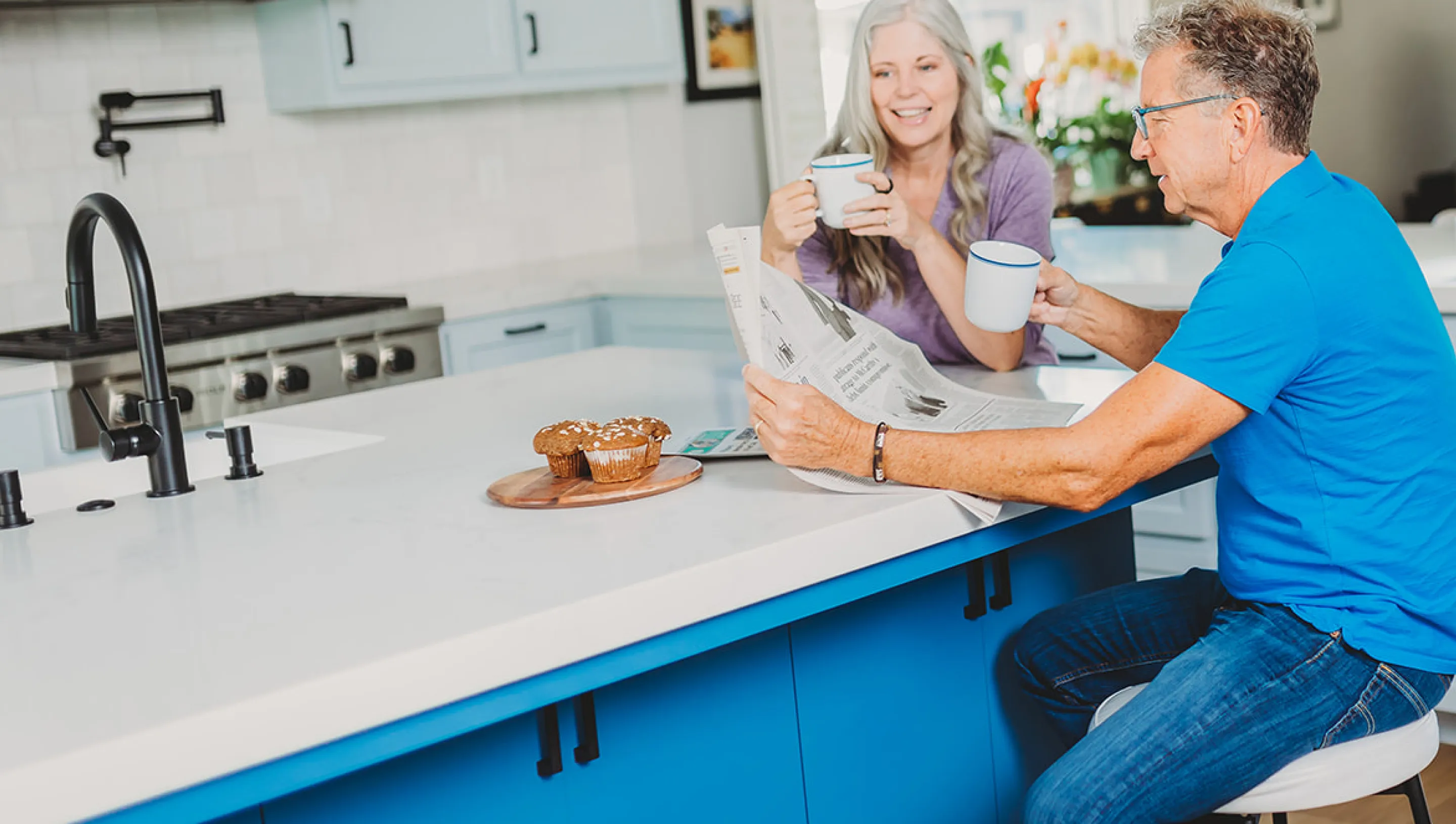 An elderly couple sharing breakfast at their kitchen island.