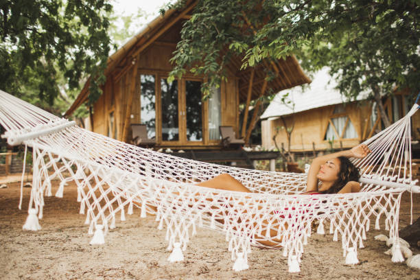 woman relaxing in a hammock on the beachside by a cabin