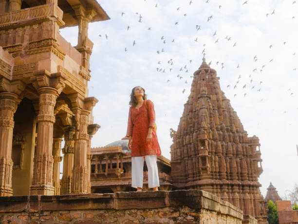 woman standing by a buiding watching the birds over her head