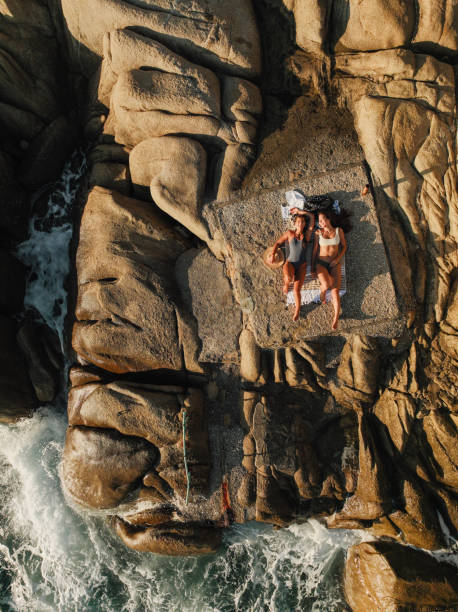 two friends laying on a bolder at the beach