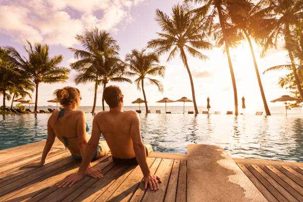 man and woman sitting by the pool at sunset