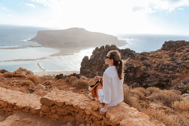 woman sitting on a ledge by the ocean