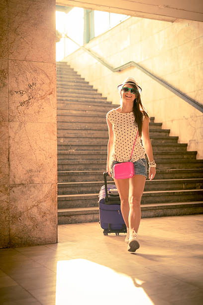 woman walking down steps in a city with a suitcase