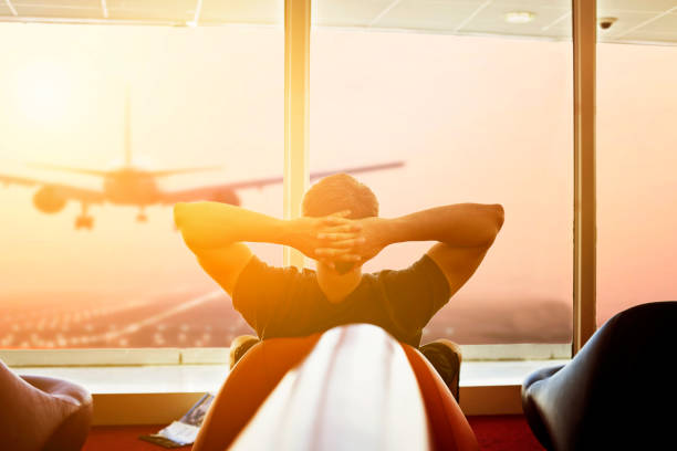 man at the airport watching an airplane through glass windows