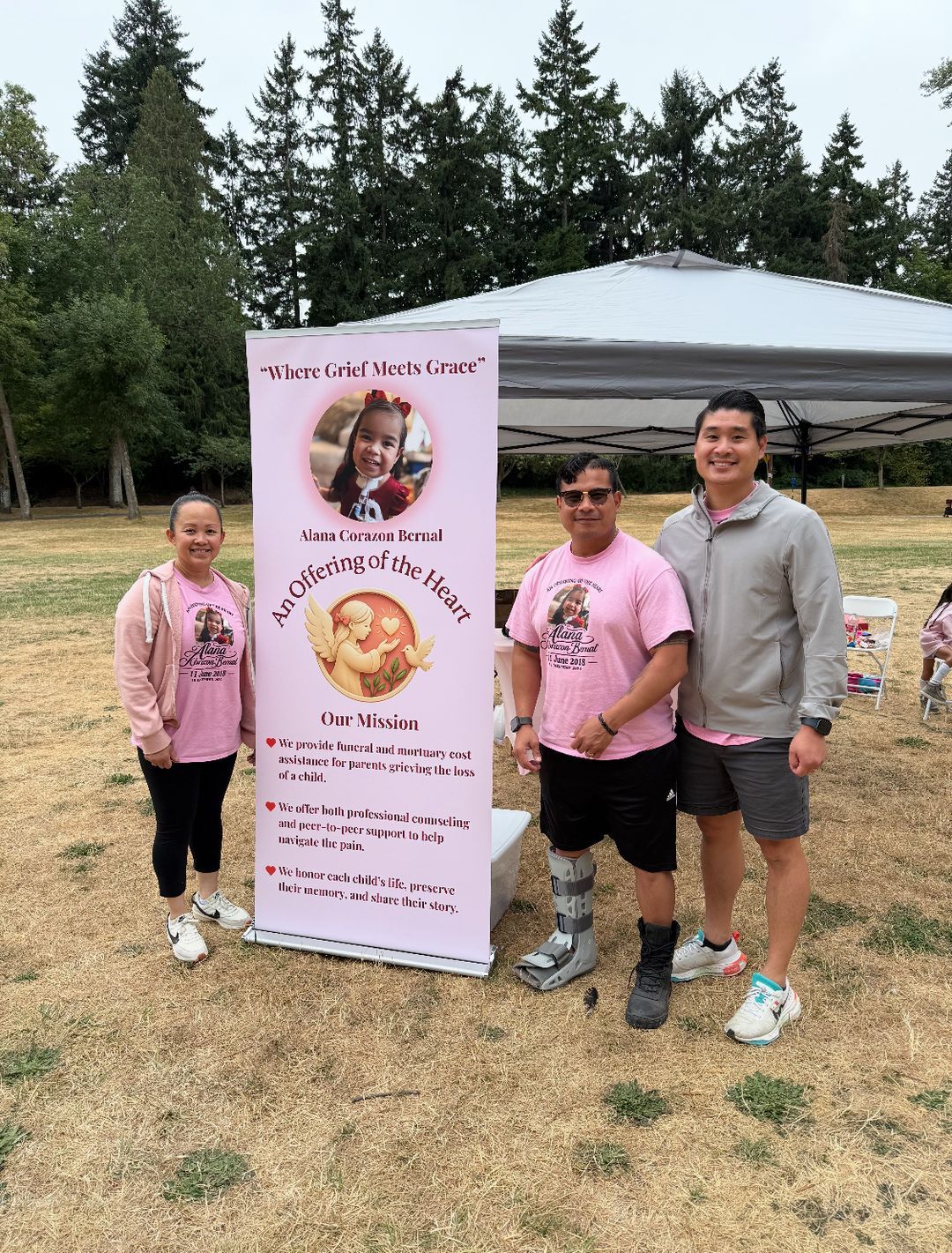 Three people beside the banner and tent at the park