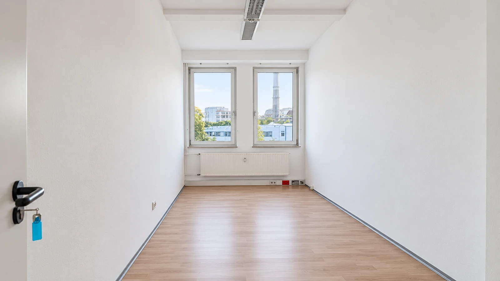 Small light-filled artist studio at GODU with two windows and wood-effect flooring