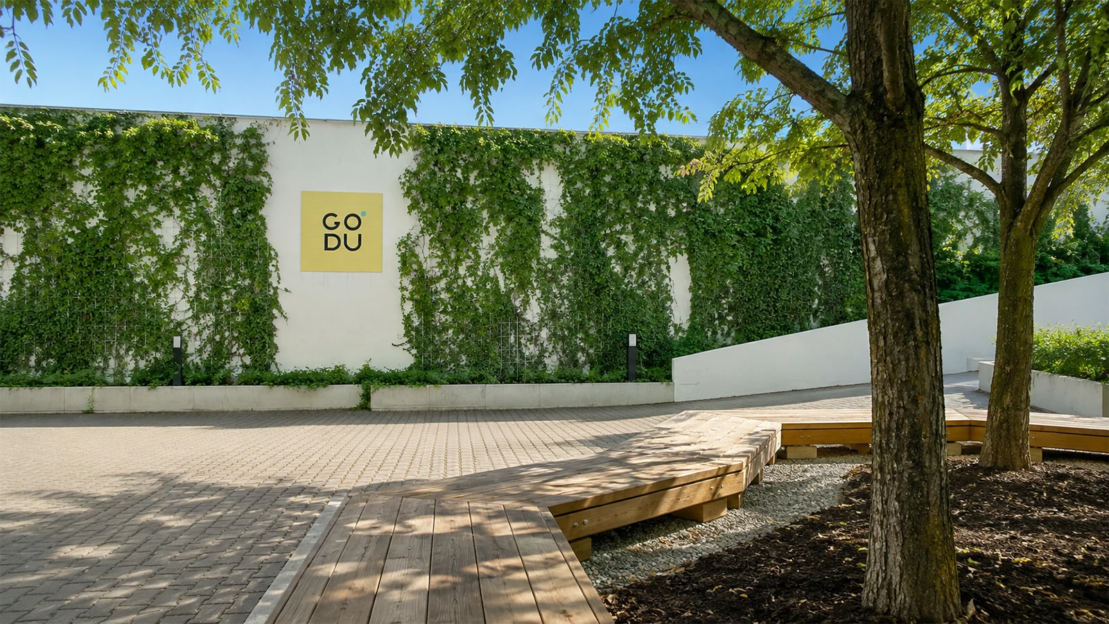 GODU courtyard with trees, wooden seating and planted walls