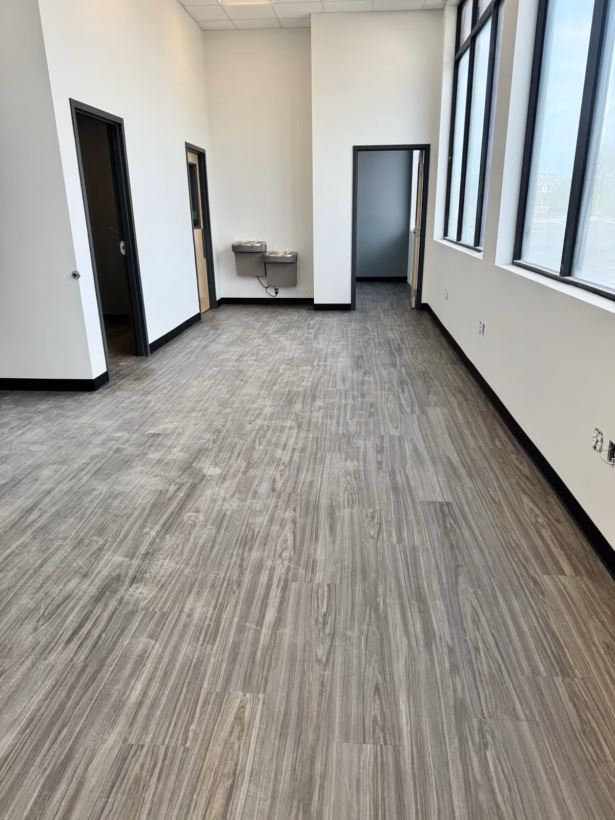 Room in Johns Creek, GA with gray wood-look vinyl plank flooring, white walls and large windows along one side