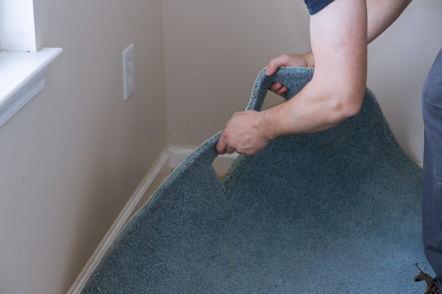 Close view of patterned carpet being tucked and secured along a stair edge.