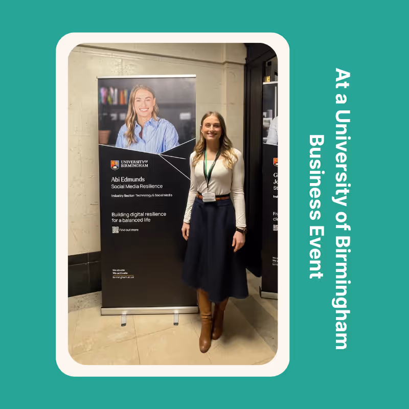 Abi Edmunds stands in front of a banner with Social Media Resilience on it, at an University of Birmingham business event. 