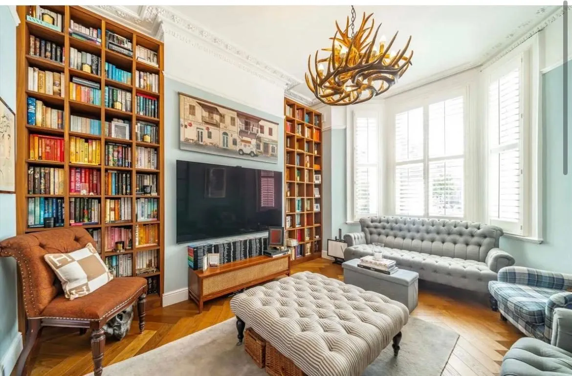 A remodelled sitting room in a Chiswick period house with built in bookshelves, a herringbone floor and tall sash windows