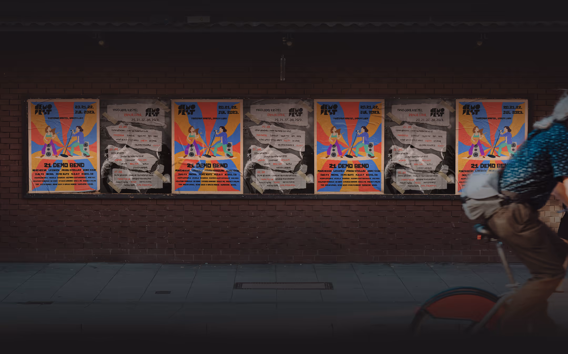 Row of six posters on a brick wall, alternating between colorful music event flyers and crumpled handwritten notes; partial figure on a bicycle rides past on the right.