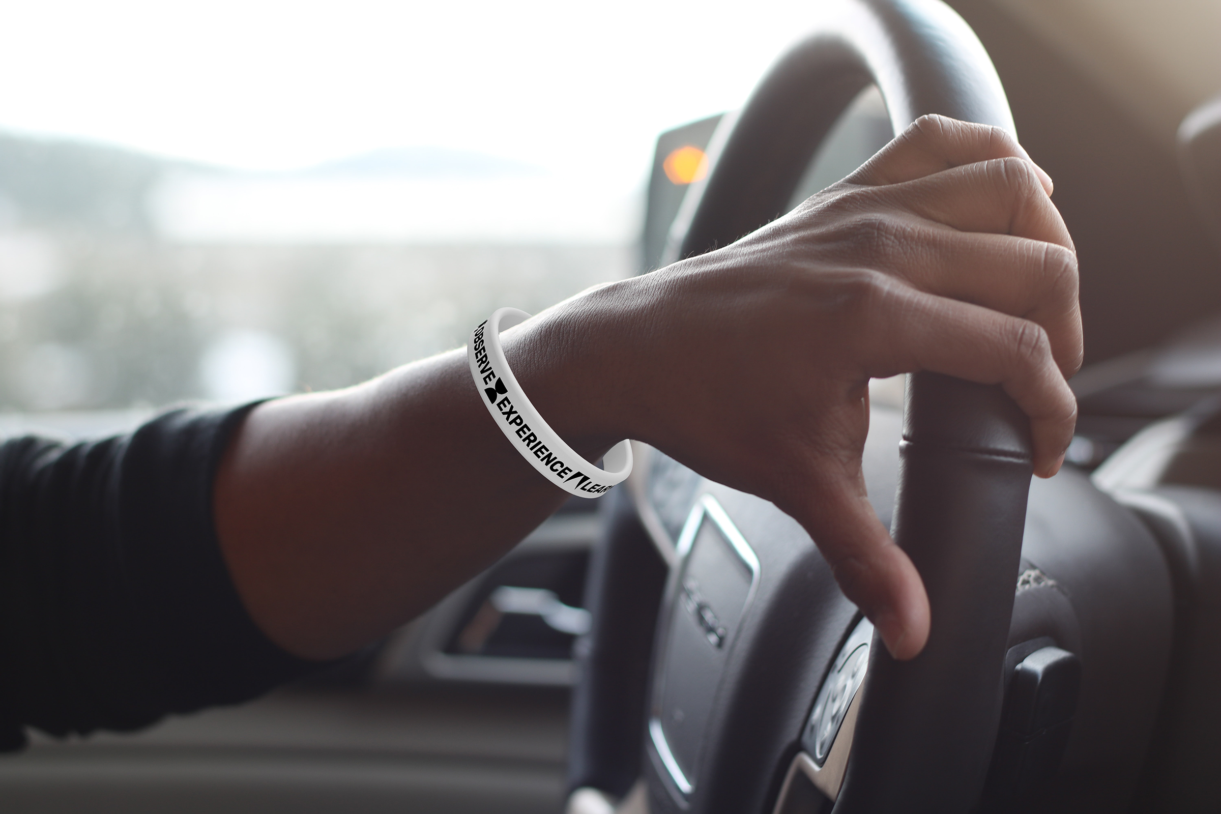 Image of a branded Griffith Observatory wristband with the new brand symbols and text that reads "Observe, Experience, Learn"